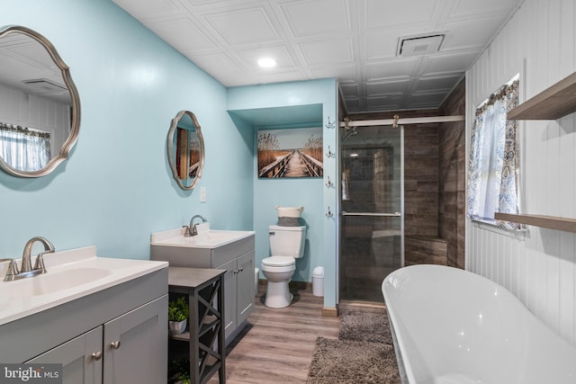 bathroom with a sink, two vanities, wood finished floors, and a shower stall