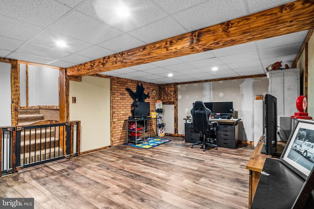 office area featuring a paneled ceiling, a wood stove, and wood finished floors