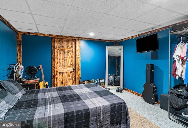 carpeted bedroom with baseboards and a paneled ceiling