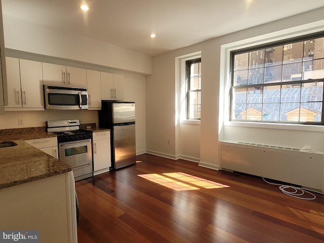 kitchen featuring stainless steel appliances, dark wood-style flooring, baseboards, white cabinets, and dark stone counters