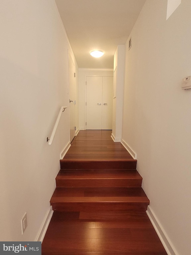 stairs with baseboards, visible vents, and wood finished floors