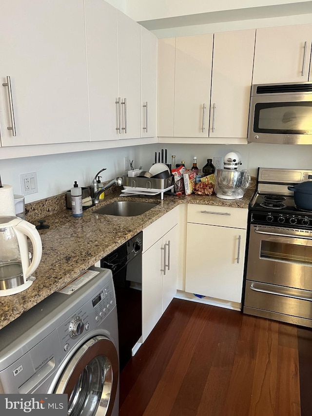 kitchen featuring appliances with stainless steel finishes, white cabinetry, sink, dark stone counters, and washer / clothes dryer