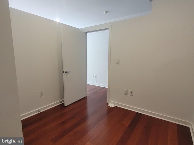 unfurnished room with dark wood-style floors and baseboards