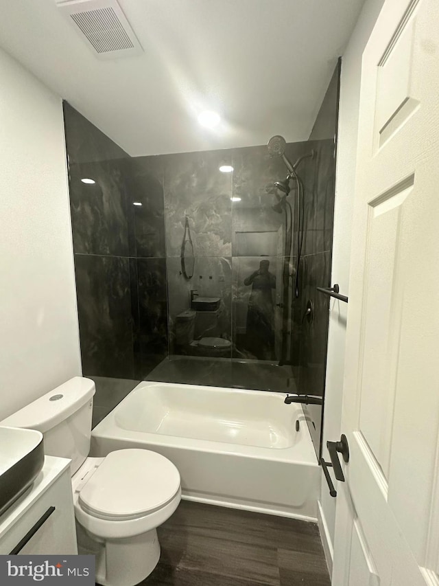 full bathroom with vanity, tiled shower / bath combo, hardwood / wood-style flooring, and toilet