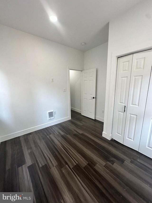 unfurnished bedroom with dark wood-type flooring and a closet