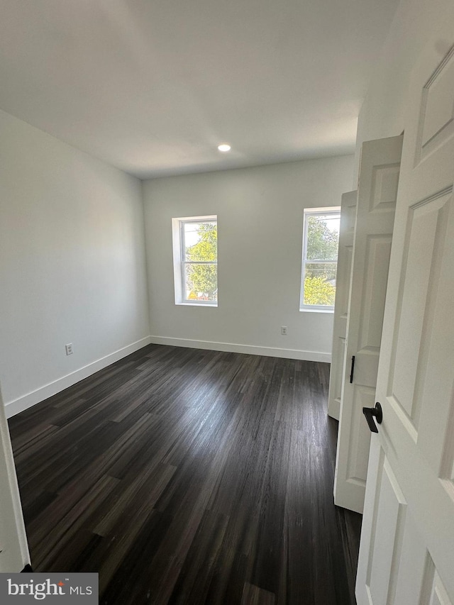 spare room with dark wood-type flooring and plenty of natural light