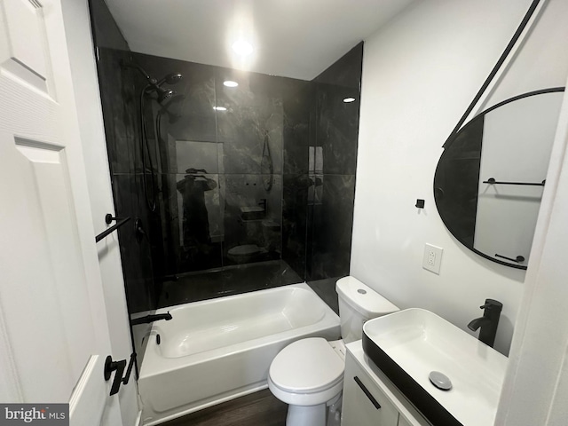 full bathroom featuring vanity, tiled shower / bath combo, hardwood / wood-style flooring, and toilet