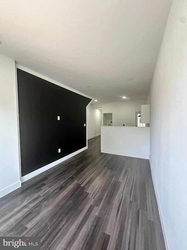 unfurnished living room featuring a textured ceiling and dark hardwood / wood-style flooring