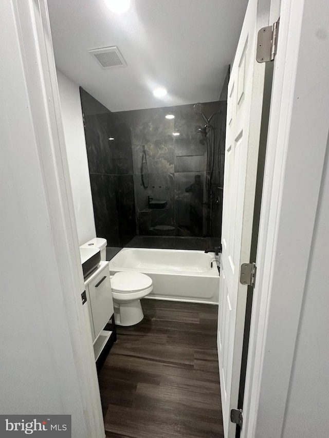 full bathroom featuring vanity, tiled shower / bath combo, wood-type flooring, and toilet