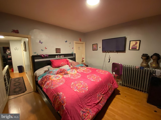 bedroom featuring radiator heating unit and light hardwood / wood-style floors