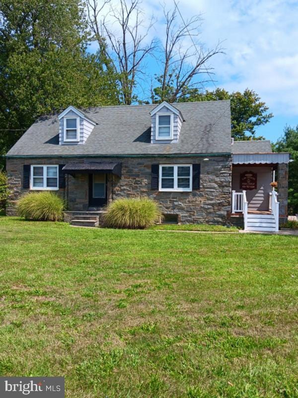 cape cod-style house featuring stone siding and a front lawn