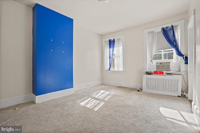 unfurnished room featuring radiator heating unit, plenty of natural light, and light colored carpet