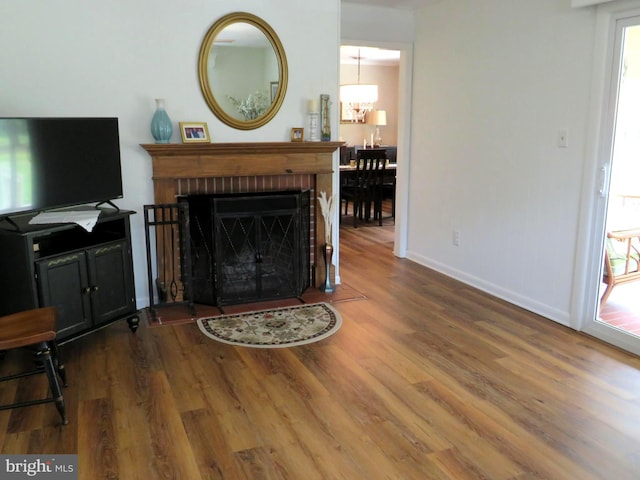 living room featuring a chandelier, a fireplace, and dark hardwood / wood-style floors