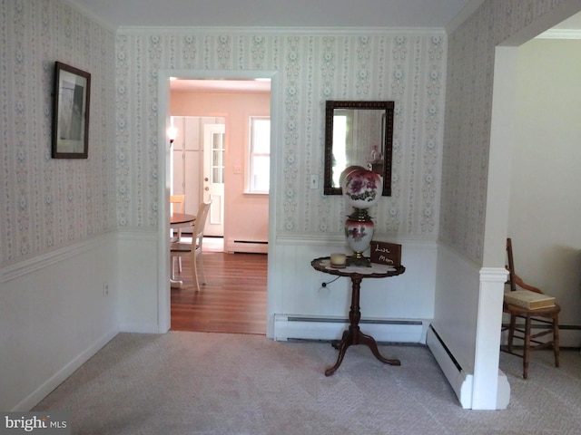 hall with wood-type flooring, baseboard heating, and crown molding