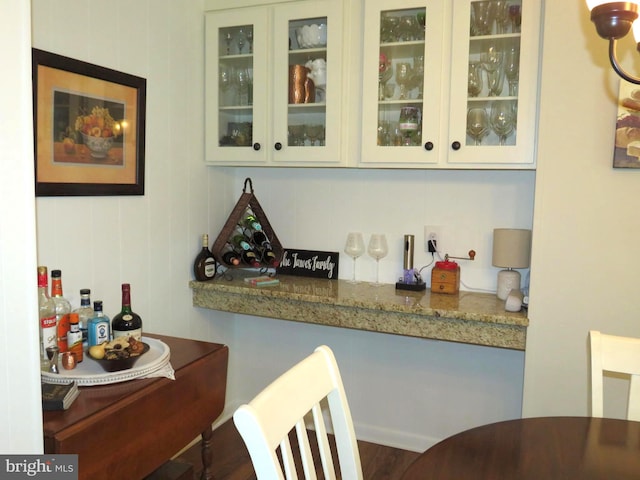 bar featuring light stone countertops and white cabinets