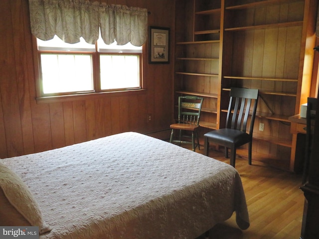 bedroom with wood walls and hardwood / wood-style flooring