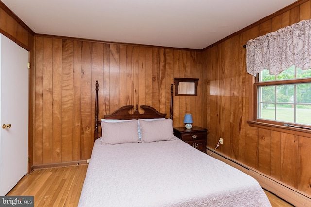 bedroom with a baseboard heating unit, wood walls, and light wood-type flooring