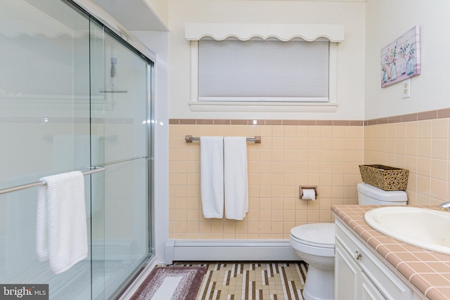 bathroom with a shower with door, toilet, baseboard heating, tile walls, and vanity