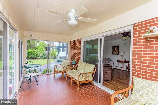 sunroom / solarium featuring a baseboard heating unit and ceiling fan