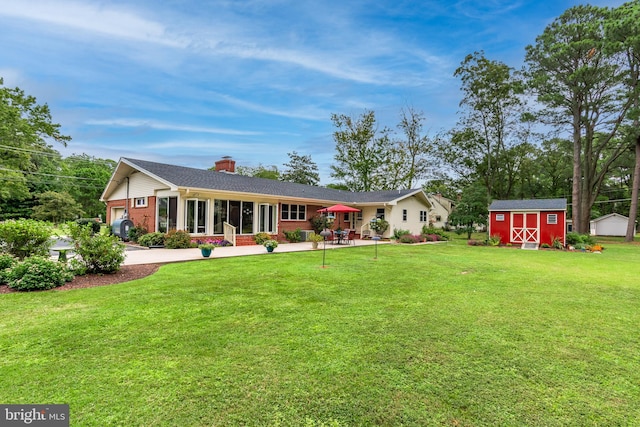 rear view of house with a yard, a storage unit, and a garage