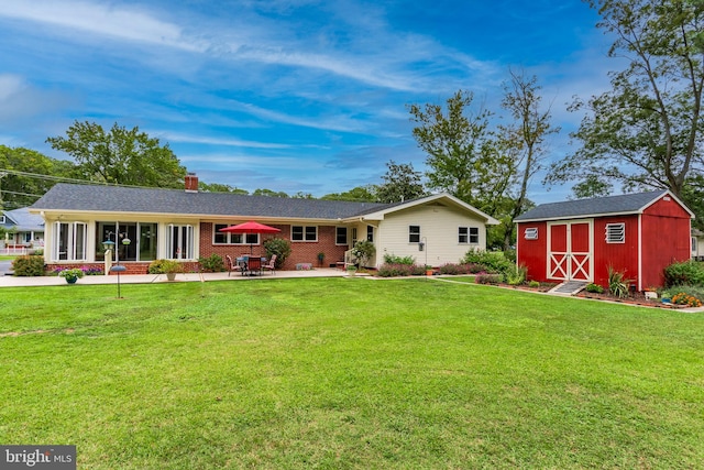 rear view of property featuring a yard, a patio, and a storage shed