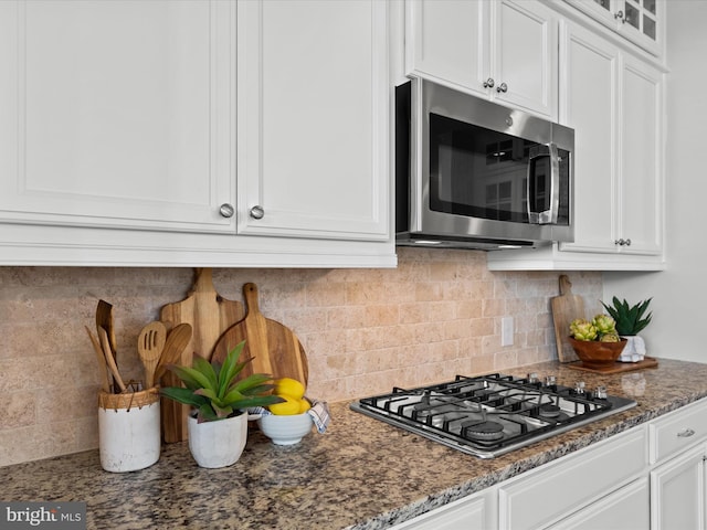 kitchen featuring white cabinets, appliances with stainless steel finishes, tasteful backsplash, and dark stone counters