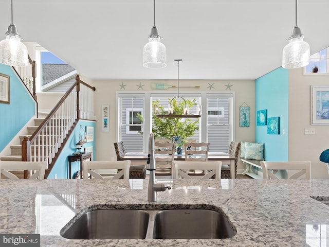 kitchen featuring light stone counters, pendant lighting, and sink