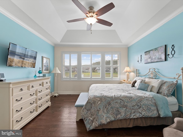 bedroom with ornamental molding, a tray ceiling, ceiling fan, and dark wood-type flooring