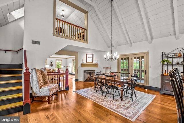 dining area featuring beamed ceiling, wood-type flooring, high vaulted ceiling, and a skylight