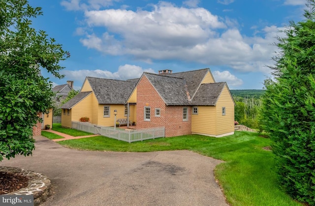 view of front of property with brick siding, a front lawn, and fence