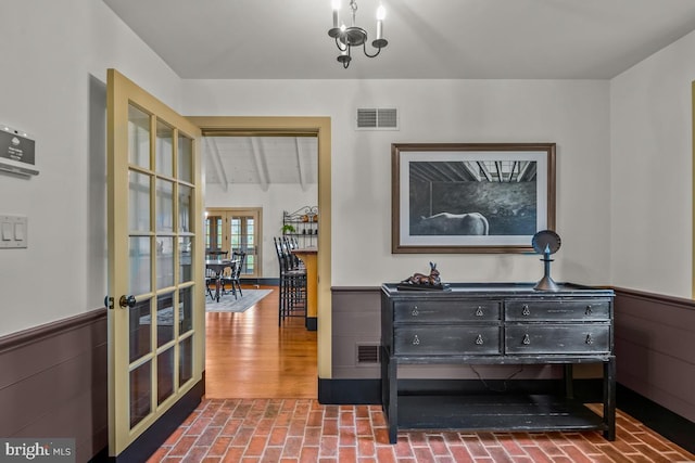 interior space with vaulted ceiling with beams, french doors, a chandelier, and wood-type flooring