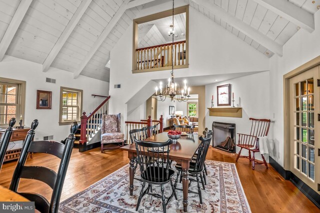 dining area featuring a chandelier, beamed ceiling, hardwood / wood-style floors, and high vaulted ceiling