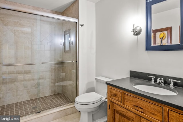 bathroom featuring a shower with door, vanity, toilet, and tile patterned flooring