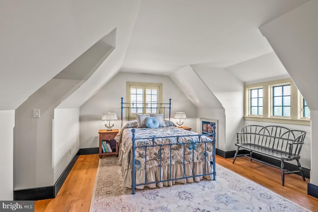 bedroom with wood-type flooring and vaulted ceiling