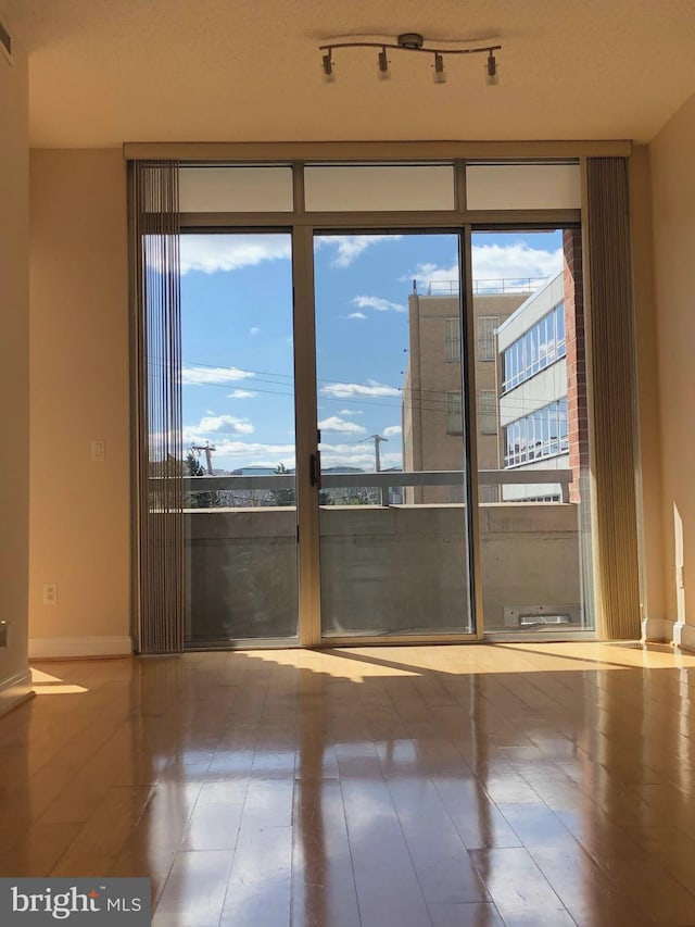 spare room with rail lighting, visible vents, baseboards, and wood finished floors