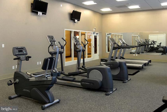 gym featuring a paneled ceiling and baseboards