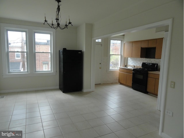 kitchen with backsplash, a notable chandelier, decorative light fixtures, light tile patterned floors, and black appliances