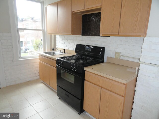 kitchen featuring light brown cabinets, light countertops, black range with gas cooktop, and a sink