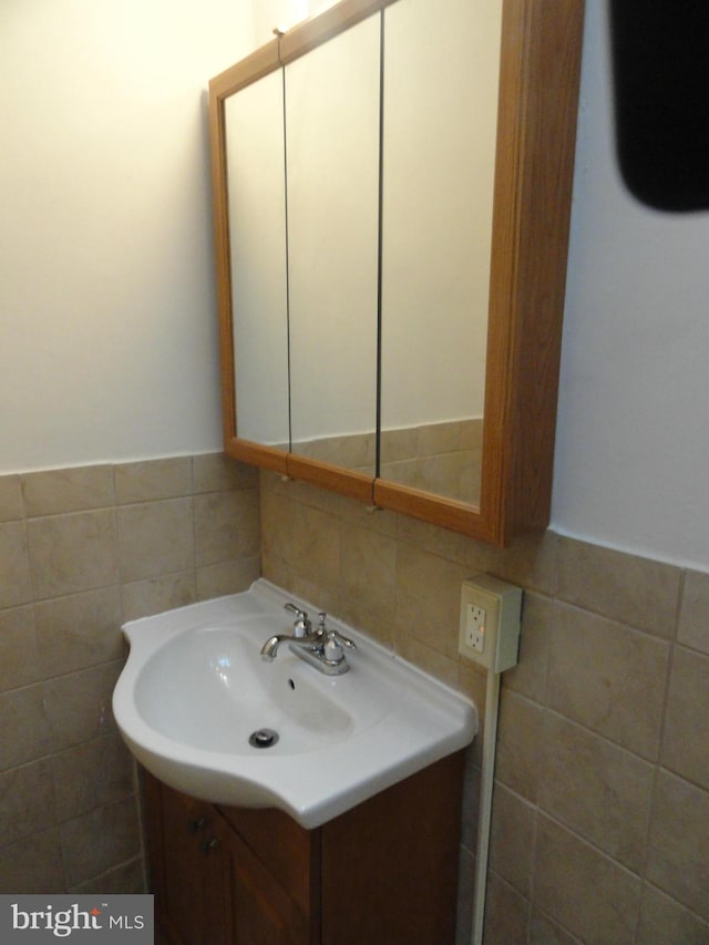 bathroom featuring decorative backsplash, vanity, and tile walls