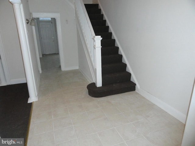 stairs with tile patterned floors and decorative columns