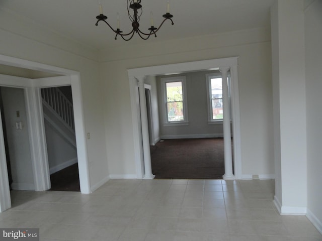 interior space featuring a chandelier, light tile patterned floors, baseboards, and stairs