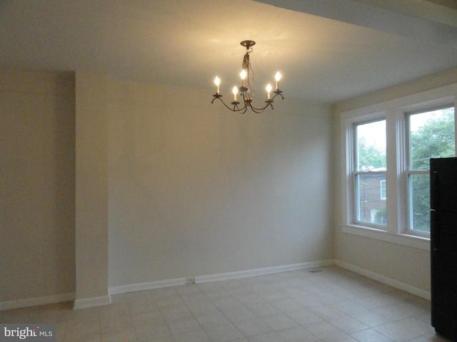 empty room with an inviting chandelier and baseboards