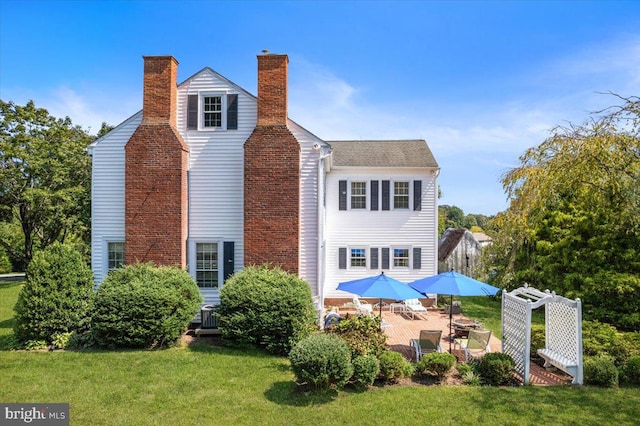 back of property featuring cooling unit, a yard, and a patio