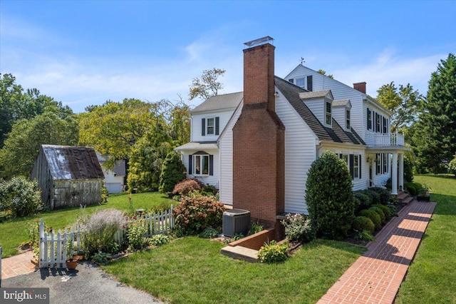 view of side of property featuring a storage shed, a yard, and central air condition unit