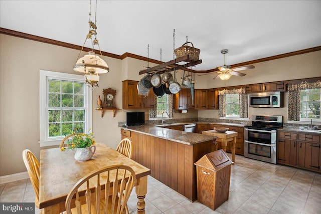 kitchen featuring pendant lighting, dark stone counters, kitchen peninsula, stainless steel appliances, and crown molding