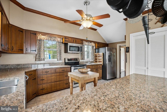 kitchen with appliances with stainless steel finishes, light tile patterned flooring, vaulted ceiling, ceiling fan, and sink