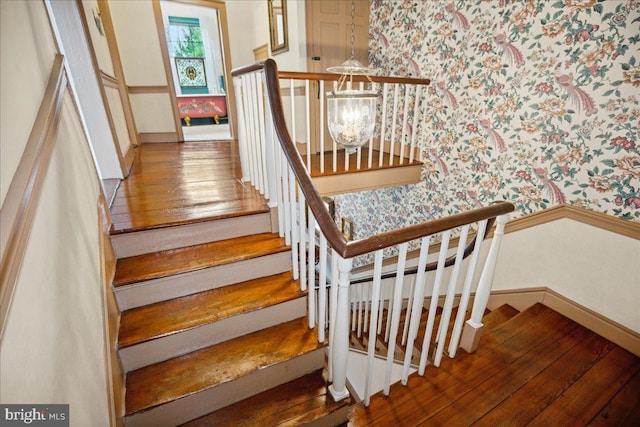 stairs with a notable chandelier and hardwood / wood-style flooring