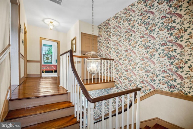 stairs featuring a notable chandelier and hardwood / wood-style floors