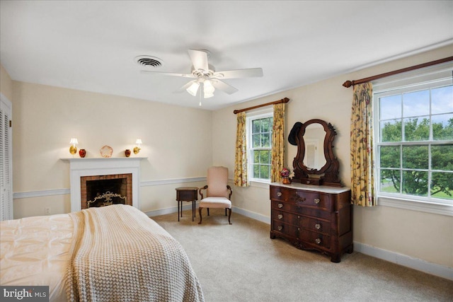 carpeted bedroom with a fireplace and ceiling fan