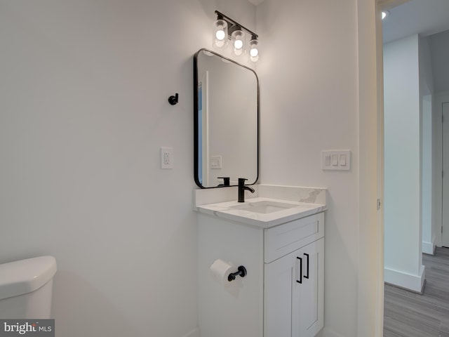 bathroom with toilet, hardwood / wood-style flooring, and vanity